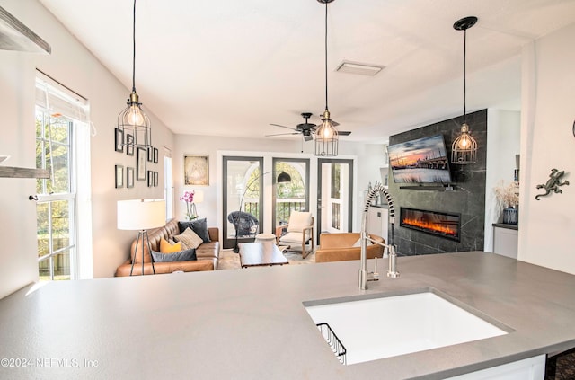 living room with a healthy amount of sunlight, ceiling fan, sink, and a fireplace