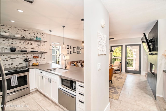 kitchen with stove, sink, white cabinetry, and a wealth of natural light