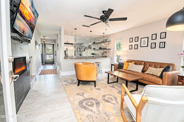 living room featuring a tiled fireplace, ceiling fan, and a healthy amount of sunlight