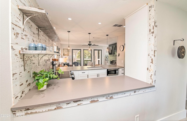 kitchen featuring decorative light fixtures, ceiling fan, kitchen peninsula, white cabinets, and sink