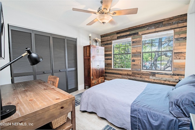 bedroom with a closet, wood walls, and ceiling fan