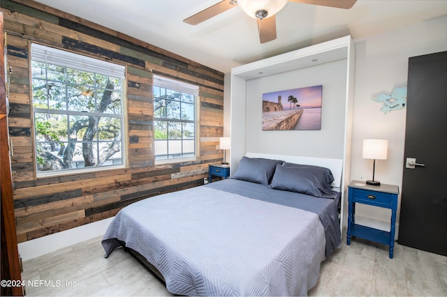 bedroom with ceiling fan and wood walls