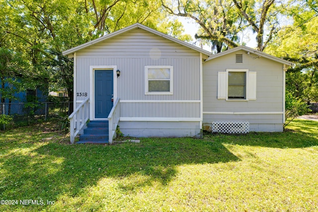 view of front of house with entry steps, crawl space, fence, and a front lawn