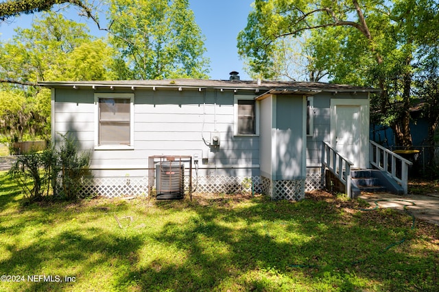 back of house featuring entry steps, central AC, a yard, and fence