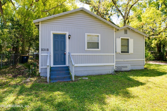 view of front facade featuring entry steps, fence, and a front lawn