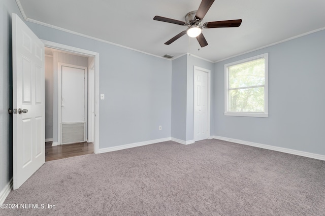 unfurnished bedroom featuring carpet floors, visible vents, crown molding, and baseboards