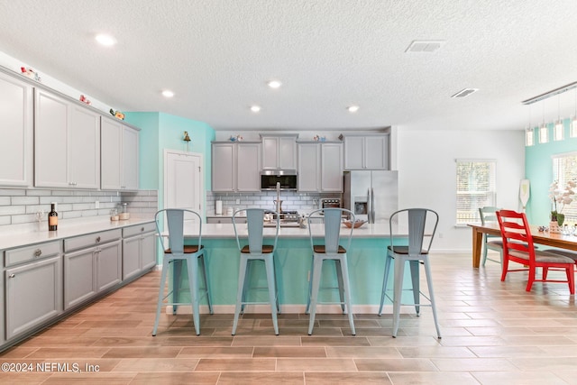 kitchen with decorative backsplash, a kitchen bar, stainless steel appliances, and an island with sink