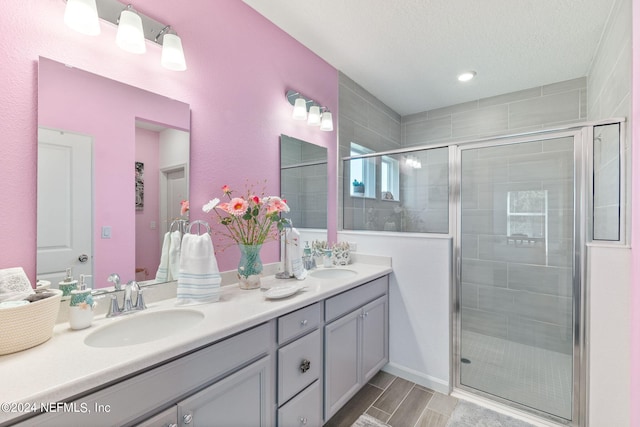 bathroom with a textured ceiling, vanity, and a shower with shower door