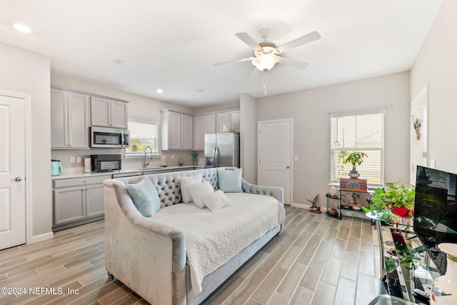 interior space with ceiling fan, light hardwood / wood-style floors, stainless steel fridge with ice dispenser, and sink