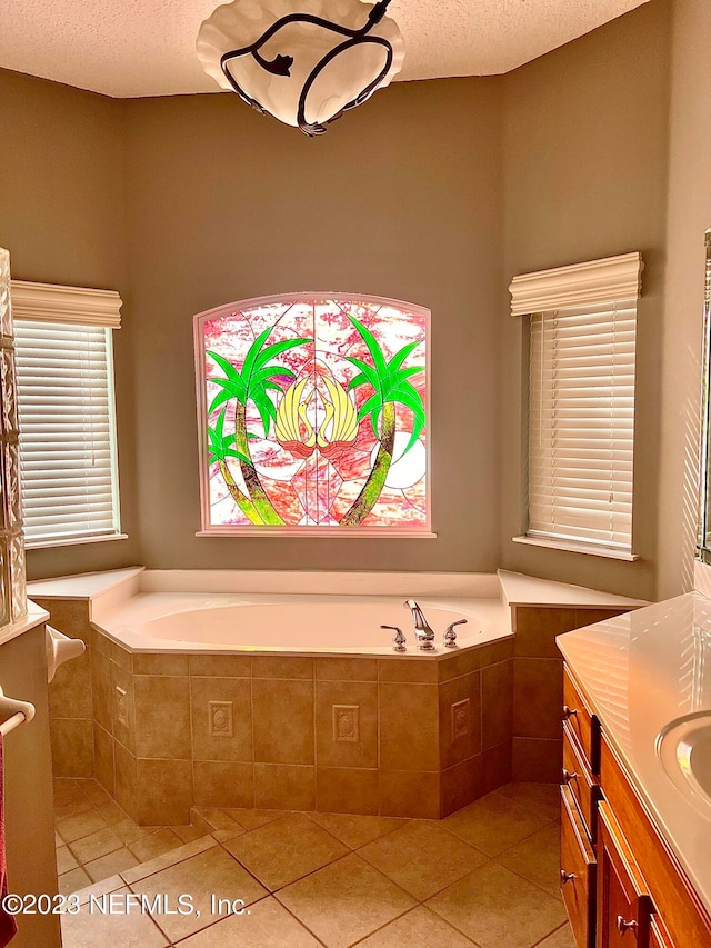 bathroom with tile floors, a textured ceiling, vanity, and tiled tub