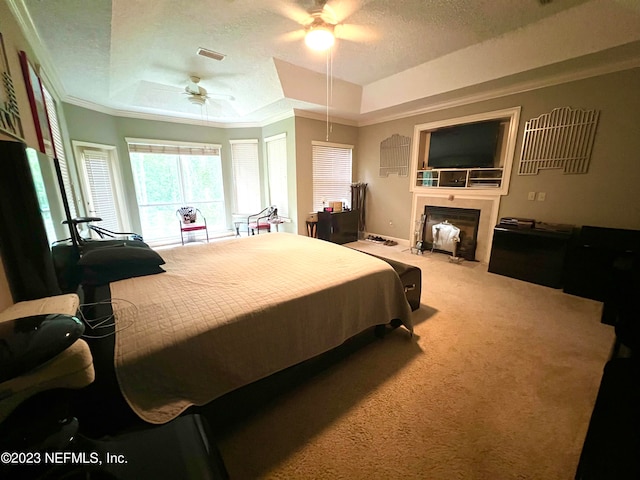 bedroom featuring crown molding, ceiling fan, a textured ceiling, carpet floors, and a raised ceiling