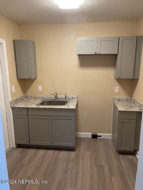 kitchen featuring wood-type flooring, gray cabinetry, and sink