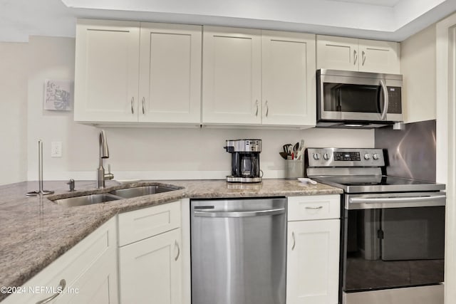 kitchen with sink, stainless steel appliances, light stone counters, and white cabinets