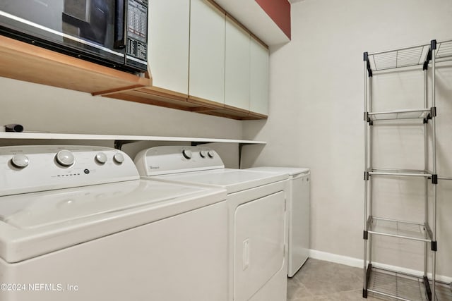 laundry room with washer and clothes dryer, cabinets, and light tile flooring