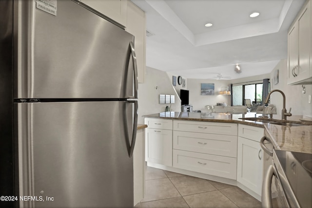 kitchen with stainless steel fridge, ceiling fan, sink, light stone countertops, and white cabinets