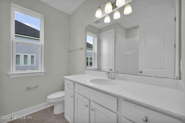 bathroom with toilet, vanity, baseboards, and tile patterned floors