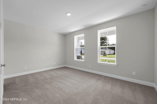 carpeted empty room with a textured ceiling and baseboards