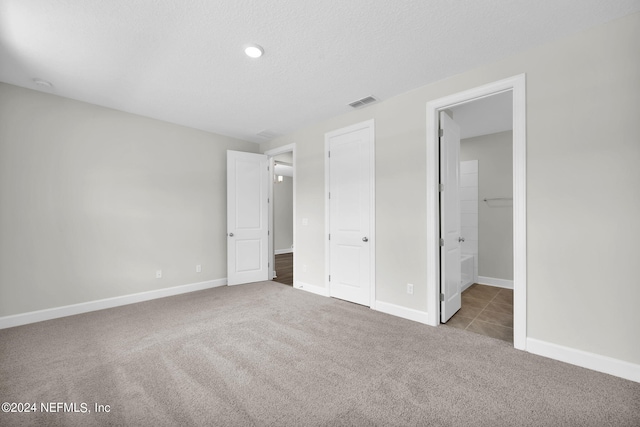 unfurnished bedroom with carpet floors, baseboards, visible vents, and a textured ceiling