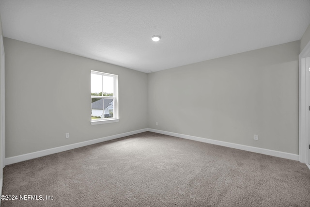 carpeted empty room featuring a textured ceiling and baseboards