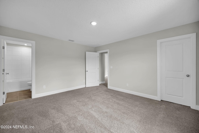 unfurnished bedroom with a textured ceiling, carpet floors, visible vents, and baseboards