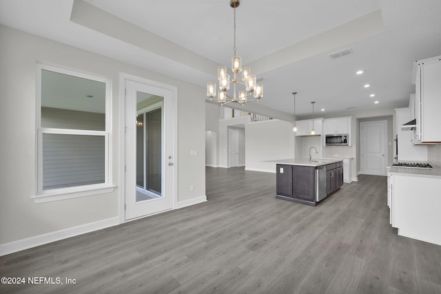 kitchen featuring hardwood / wood-style flooring, hanging light fixtures, a center island with sink, and white cabinets