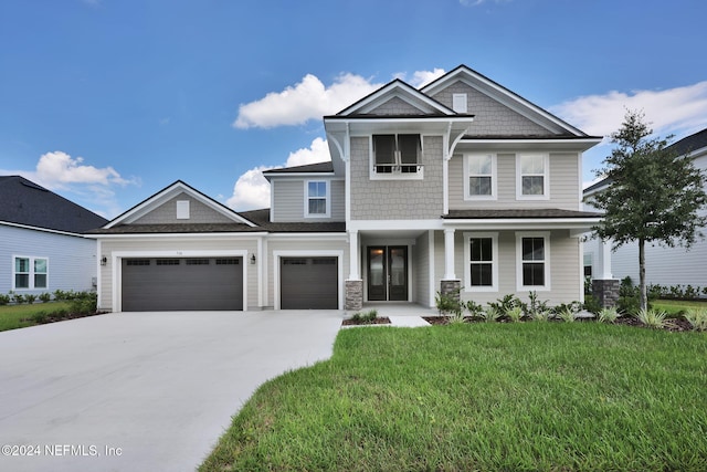 view of front facade featuring a garage, driveway, covered porch, and a front yard