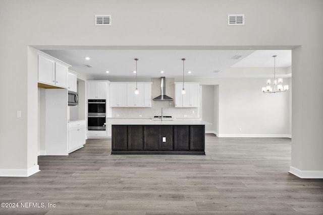 kitchen with stainless steel appliances, wall chimney range hood, light countertops, and visible vents