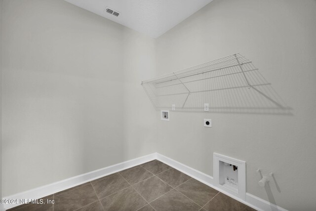 laundry area with dark tile patterned flooring, hookup for a gas dryer, hookup for a washing machine, and hookup for an electric dryer