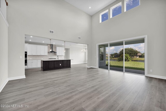 unfurnished living room with a wealth of natural light, a high ceiling, and light hardwood / wood-style flooring