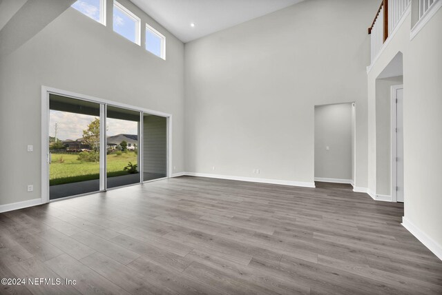 unfurnished living room with hardwood / wood-style flooring and a towering ceiling