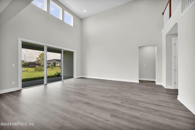 unfurnished living room featuring dark wood-style floors, a high ceiling, baseboards, and recessed lighting