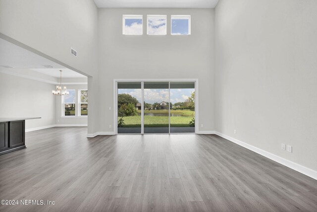 unfurnished living room with a notable chandelier, hardwood / wood-style floors, and a towering ceiling