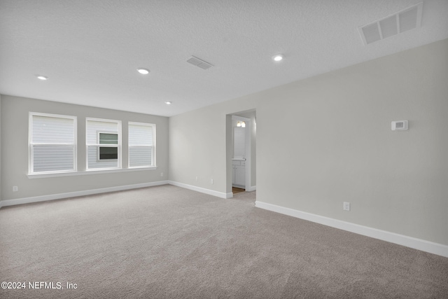 carpeted empty room featuring a textured ceiling