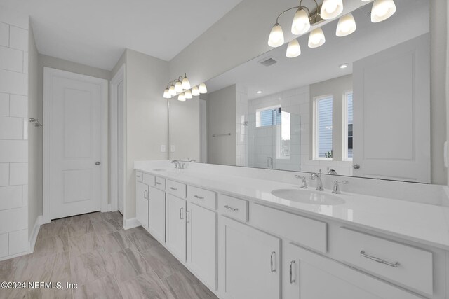 full bath with visible vents, a sink, a tile shower, and double vanity