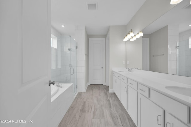 bathroom with double vanity, a stall shower, visible vents, a bath, and a sink