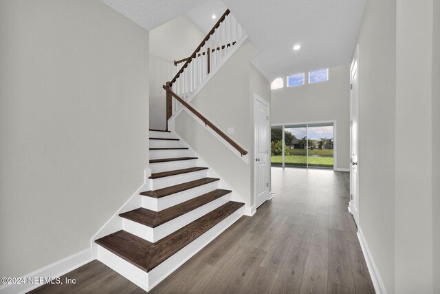 staircase with hardwood / wood-style flooring and a towering ceiling