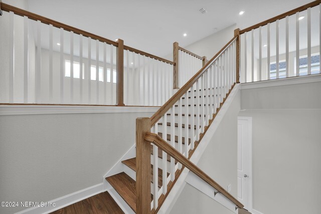 staircase with plenty of natural light and wood-type flooring