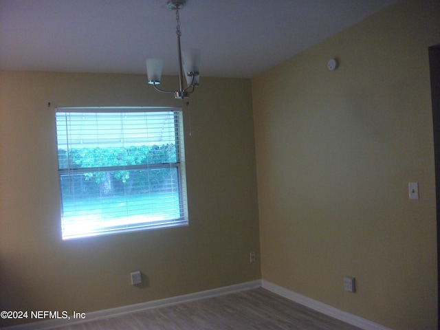 spare room featuring hardwood / wood-style floors and a notable chandelier