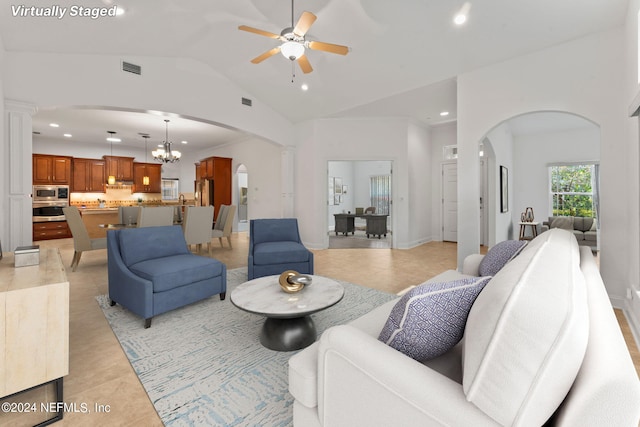 living room featuring lofted ceiling, light tile floors, and ceiling fan with notable chandelier