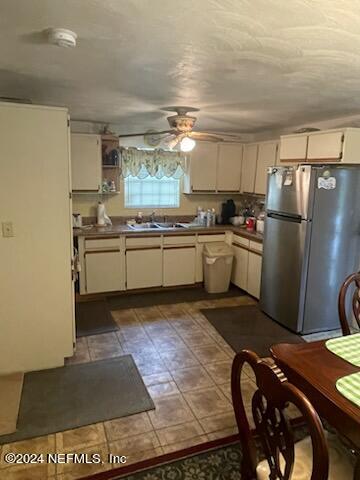 kitchen featuring ceiling fan, stainless steel fridge, sink, and tile flooring