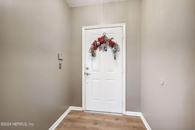 doorway to outside featuring a textured ceiling and light wood-type flooring