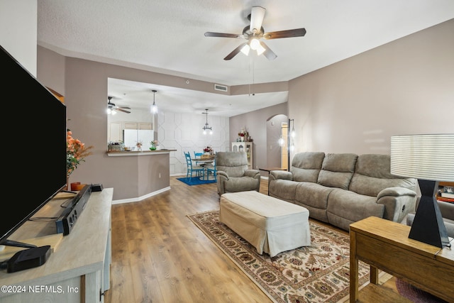 living room with ceiling fan, hardwood / wood-style floors, and a textured ceiling