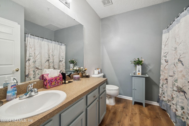 bathroom featuring hardwood / wood-style floors, vanity, toilet, and a textured ceiling