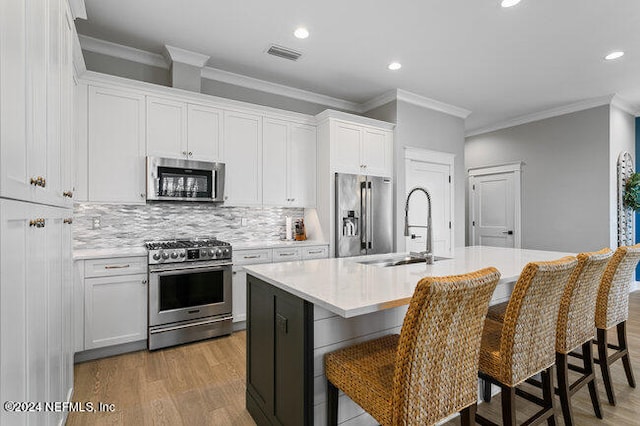 kitchen featuring white cabinets, a breakfast bar area, stainless steel appliances, and a kitchen island with sink