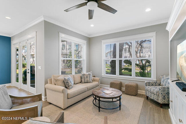 living room featuring ornamental molding, plenty of natural light, ceiling fan, and light wood-type flooring