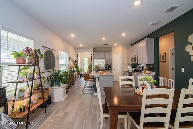 dining room with a textured ceiling and light wood-type flooring