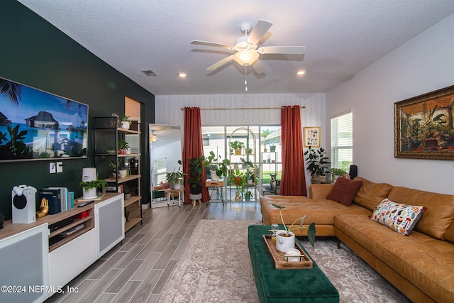 living room with light hardwood / wood-style floors, ceiling fan, and a textured ceiling