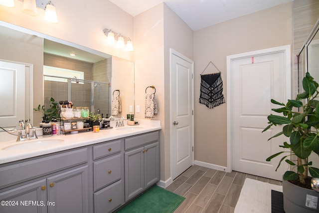 bathroom with dual vanity and a shower with shower door