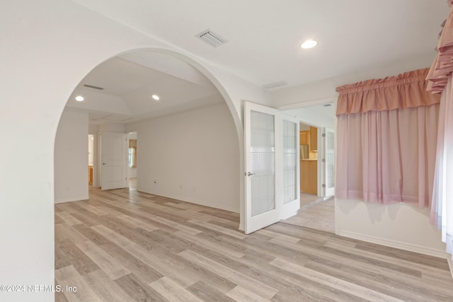 spare room featuring french doors and light hardwood / wood-style flooring