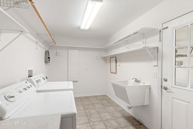 washroom featuring sink, light tile floors, hookup for a washing machine, a textured ceiling, and separate washer and dryer